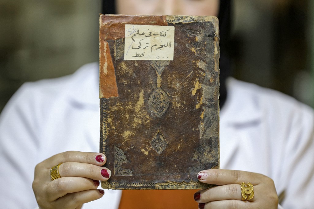A conservator holds up a Turkish-language astronomy manuscript undergoing restoration at the Iraqi Manuscript House's resoration lab in Iraq's capital Baghdad, Dec. 6, 2022. (Photo: Sabah Arar/AFP)