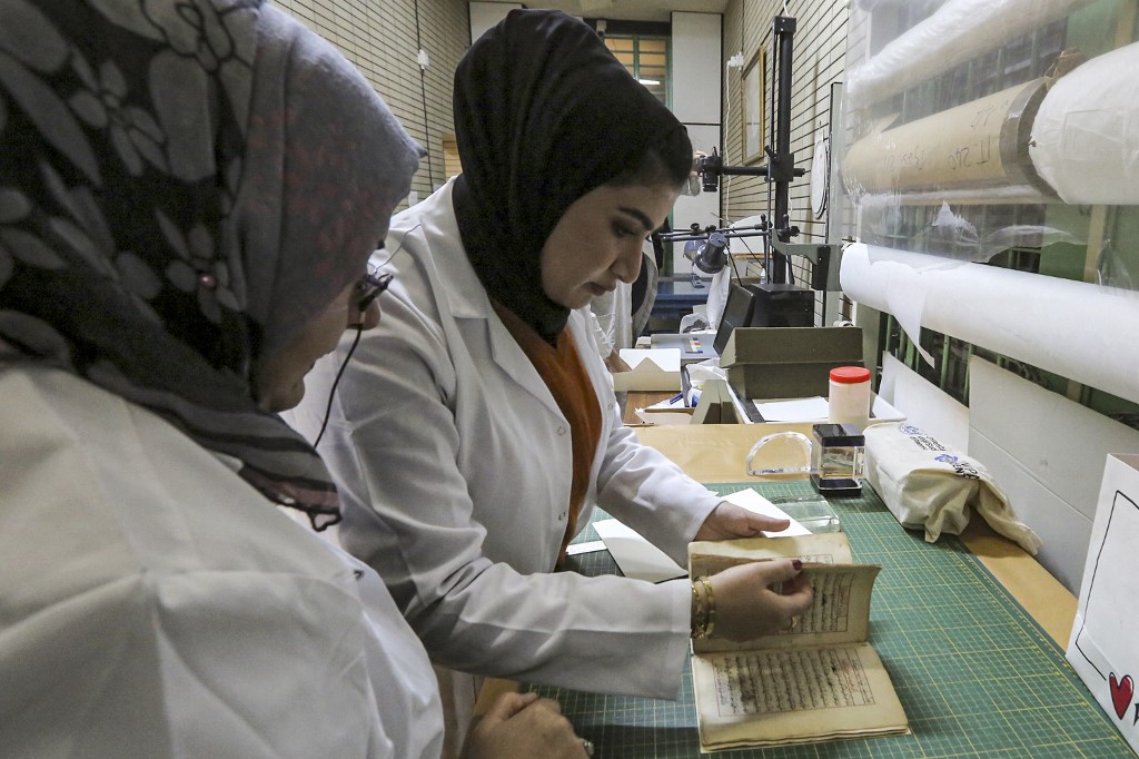 A conservator holds up a Turkish-language astronomy manuscript undergoing restoration at the Iraqi Manuscript House's resoration lab in Iraq's capital Baghdad, Dec. 6, 2022. (Photo: Sabah Arar/AFP)