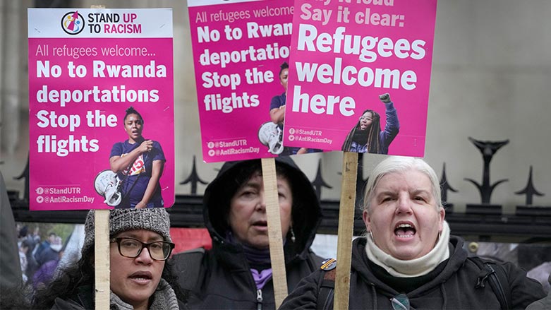 Stand Up To Racism campaigners hold banners outside the High Court in London, Monday, Dec. 19, 2022. (Photo: Kirsty Wigglesworth/ AP)