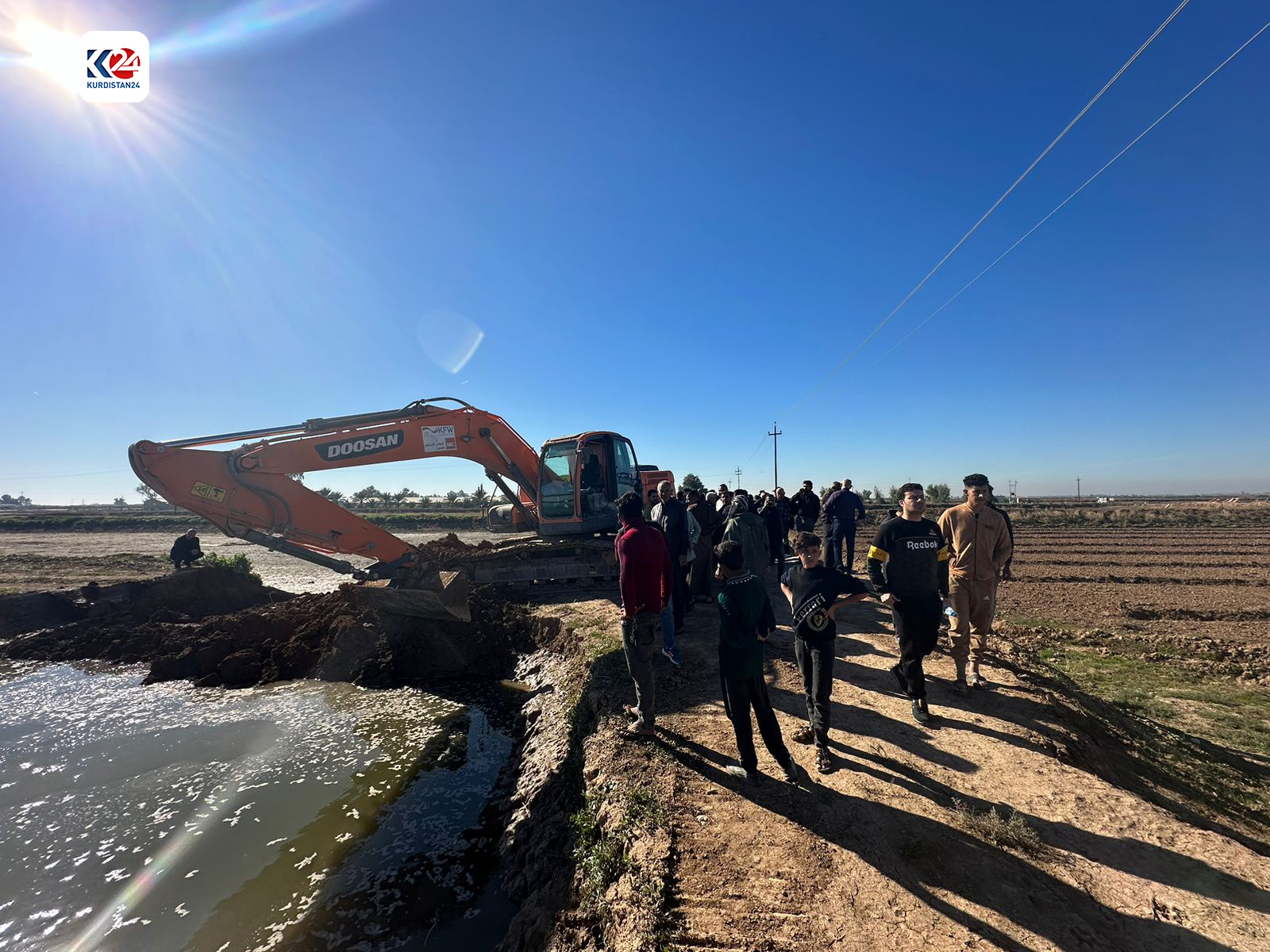 Fish farm owners and workers gather around a power shovel that is dispatched by local authorities to destroy a fish farm in Kirkuk's Daqooq distrcit, Dec. 3, 2023. (Photo: Dilan Barzan/Kurdistan 24)