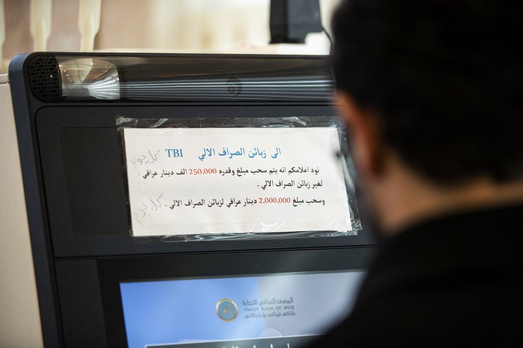 Logistics officer at a foreign oil compnay Al-Harith Hassan withdraws cash from an ATM in Iraq's southern city of Basra, Dec. 8, 2023. (Photo: Hussein Faleh/AFP)