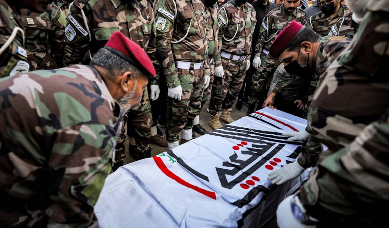 Members of the group Kataeb Hezbollah drapes the body of their fallen comrade Hassan Hammadi al-Amiri with the PMF flag during his funeral in Baghdad, Dec. 26, 2023. (Photo: Ahmad Al-Rubaye/AFP)