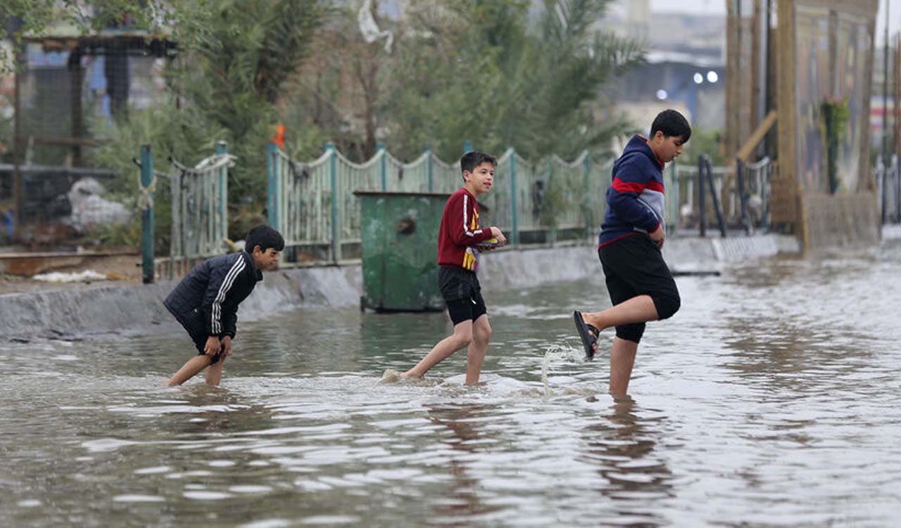 Iraqi children cross a flooded street in the Iraqi capital Baghdad after heavy rains, Dec. 24, 2022. (Photo: Sabah Arar/AFP)