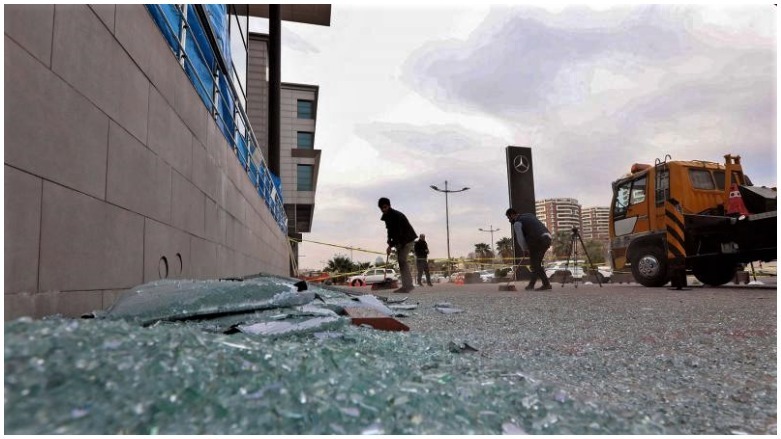 A worker cleans shattered glass on Feb. 16, 2021 outside a damaged shop following a rocket attack the previous night in the Kurdistan Region’s capital of Erbil. (Photo: AFP)
