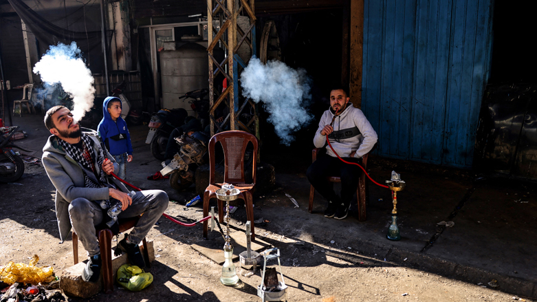 Lebanese men smoke waterpipes as they take a break outside their workshop in an alley of the northern city of Tripoli's empoverished neighbourhood of Bab al-Tabbaneh, Jan. 22, 2022. (Photo: Joseph Eid/AFP)