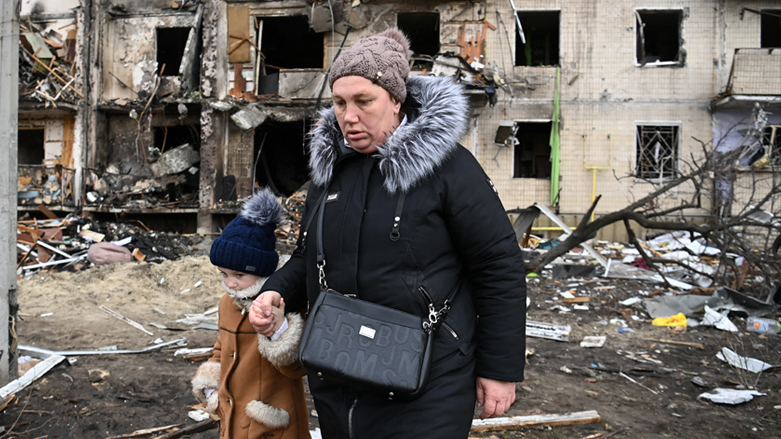 A woman with a child walks in front of a damaged residential building at Koshytsa Street, a suburb of the Ukrainian capital Kyiv, where a military shell allegedly hit, on Feb. 25, 2022. (Photo: Daniel Leal/AFP)