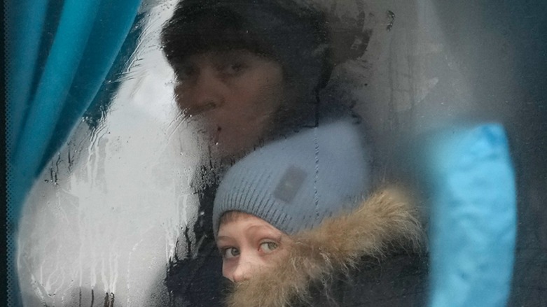 A woman and child peer out of the window of a bus as they leave Sievierodonetsk, the Luhansk region, eastern Ukraine, Feb. 24, 2022. (Photo: Andreea Alexandru/AP)