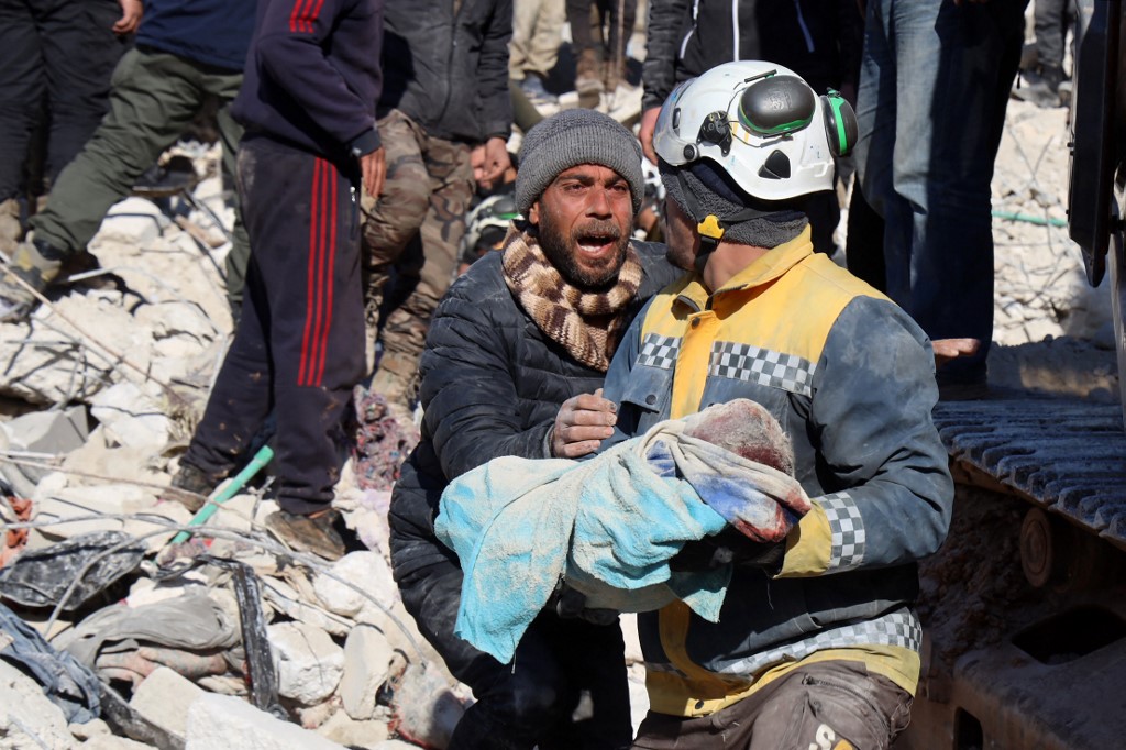 A man reacts as the body of his baby pulled out from the rubble, is taken away by a Syrian White Helmet rescue worker, in the town of Harim in Syria's rebel-held northwestern Idlib province on the border with Turkey, Feb. 8, 2023. (Photo: Mohammed Al-Rifai/AFP)