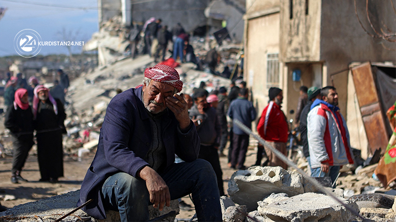 رجلٌ مسن يجلس على ركام أحد الأبنية المدمّرة في تركيا- عدسة K24