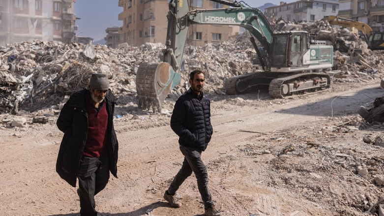 People walk past collapsed buildings in Antakya, southern Turkey on February 20, 2023 (Photo: Sameer Al-Doumy/AFP)