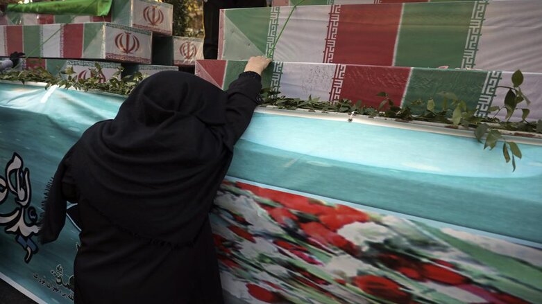 An Iranian woman mourns next to flag-draped caskets of unknown soldiers who were killed during the 1980-88 Iran-Iraq war, whose remains were recently recovered from former battlefields, during their funeral in Tehran, Iran, Thursday, Jan. 6