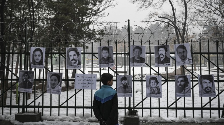 A boy looks at portraits displayed on a fence by the Social Association of Afghan Justice Seekers (SAAJS) of Afghan nationals who died in previous wars in Afghanistan, in Kabul on January 9, 2022. (Photo: Mohd RASFAN / AFP)