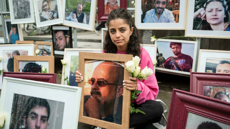 Syrian campaigner Wafa Mustafa displays photos of victims of the Syrian regime, holding a picture of her missing father. (Photo: Thomas Lohnes/AFP)