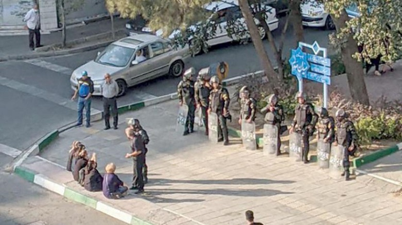 Tahran Meydanı'nda güvenlik güçlerinin önünde başları açık şekilde oturan İranlı kadınlar (AFP)