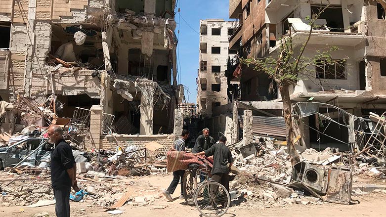 People stand in front of damaged buildings, in the town of Douma, the site of a suspected chemical weapons attack, near Damascus, Syria, Monday, April 16, 2018. (Photo: Hassan Ammar/ AP)