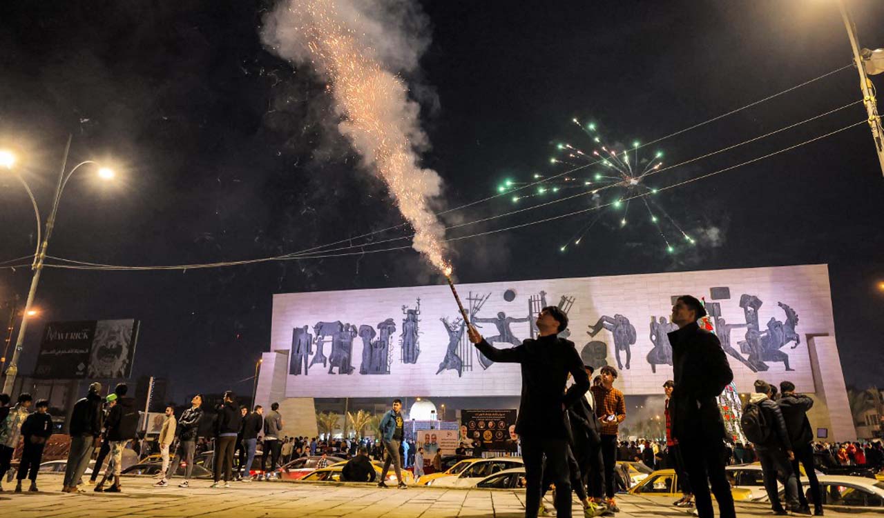 A man fires a flare before midnight in Tahrir Square in the centre of Baghdad ahead of New Year's Eve celebrations, Dec. 31, 2023. (Photo: Ahmed Al-Rubaye/AFP)