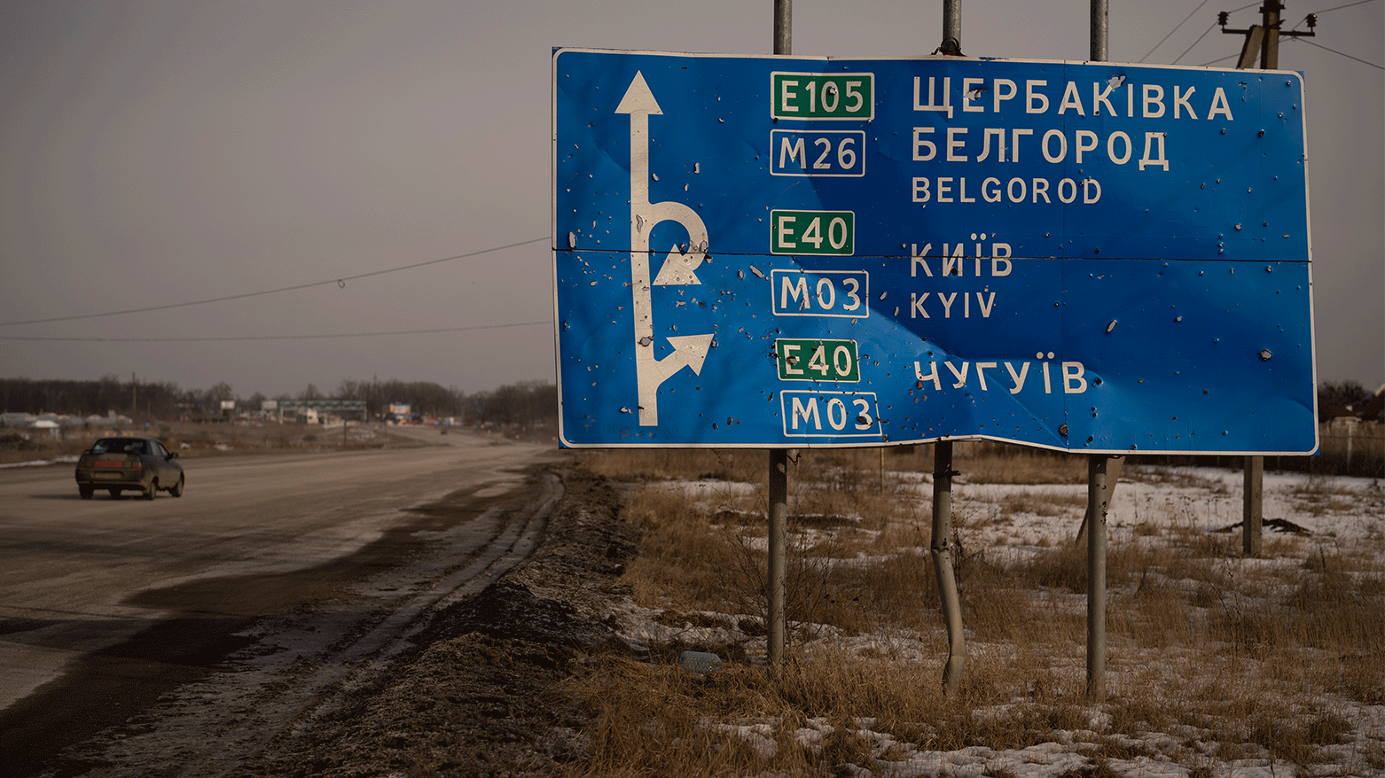 A car drives by bullet and shrapnel riddled road sign on the road to the Russian city of Belgorod, Feb. 24, 2023. (Photo: AP)