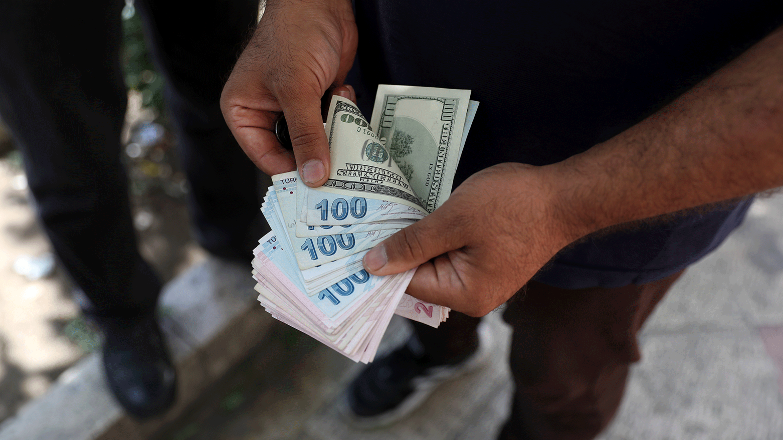 A street money exchanger poses for a photo without showing his face as he counts foreign banknotes in Ferdowsi street, Tehran's go-to venue for foreign currency exchange, Iran, June 12, 2022. (Photo: AP)