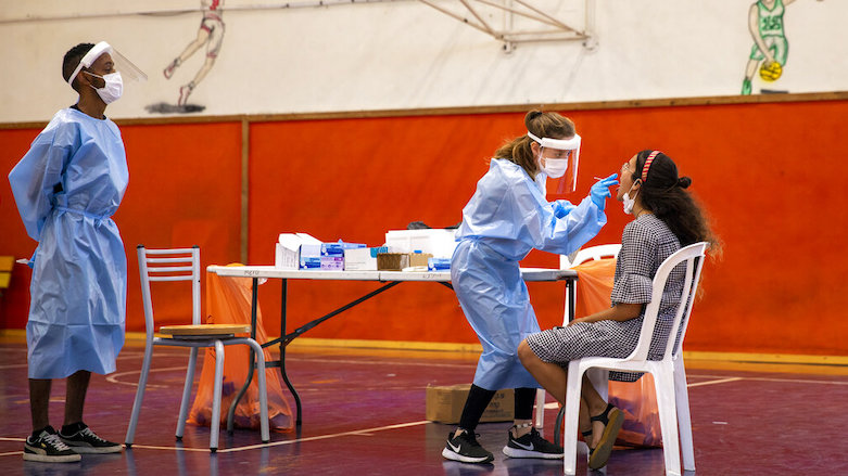 A medical worker tests an Israeli youth for the coronavirus at a basketball court turned into a coronavirus testing center, in Binyamina, Israel, June 29, 2021. (Photo: Ariel Schalit/AP)