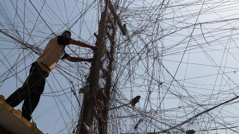 An Iraqi man connects overhead cables providing generator electricity to homes and businesses who can afford it in Sadr City, east of the capital Baghdad, on July 2, 2021. (Photo: Ahmad al-Rubaye)