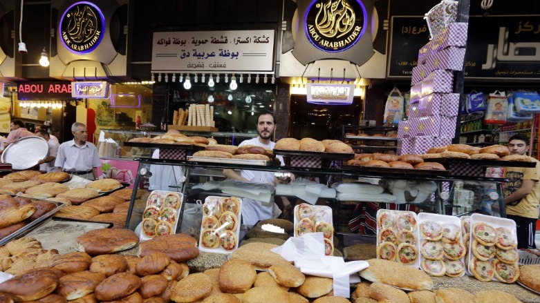 A Syrian man displays bread and traditional sweets for sale in Damascus' Midan neighborhood as people shop prior to breaking their fast during the Muslim holy month of Ramadan on June 21, 2016. (Photo: Louai Beshara / AFP)