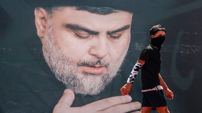 A mask-clad youth walks in front of a large poster of Iraq's populist Shiite Muslim cleric Moqtada Sadr, in Sadr City, east of the capital Baghdad, July 15, 2021. (Photo: Ahmad al-Rubaye/AFP)