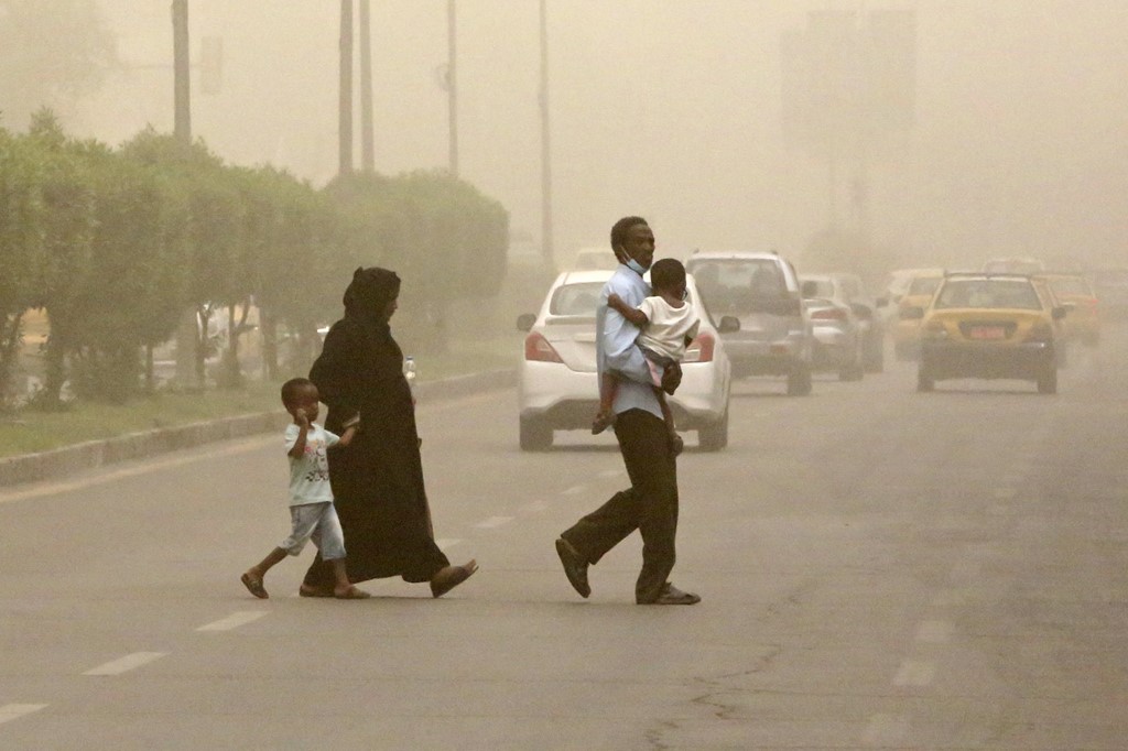 A family crosses a street during a sandstorm in the Iraqi capital Baghdad, July 3, 2022. (Photo: Ahmad Al-Rubaye/AFP)
