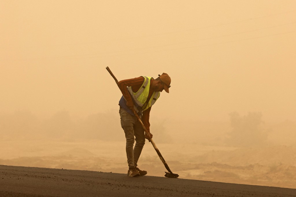A worker sweeps a road during a sandstorm in Iraq's Diyala province, July 3, 2022. (Photo: Ahmad Al-Rubaye/AFP)
