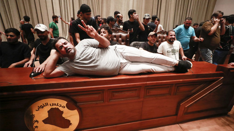 A supporter of the Iraqi cleric Moqtada Sadr, lies on the desk of the speaker of the Iraqi parliament, as demonstrators gather inside the Iraqi parliament in the capital Baghdad's high-security Green Zone, July 27, 2022. (Photo: Ahmad Al-Ru