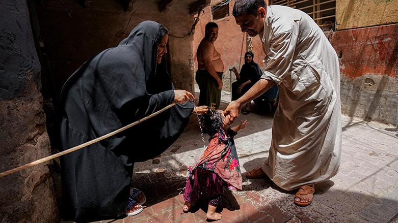 A woman sprays her children with a water hose during a heat wave outside his home in the al Fadhil neighborhood in Baghdad, Iraq, July 6, 2023. (Photo: AP/ Hadi Mizban)