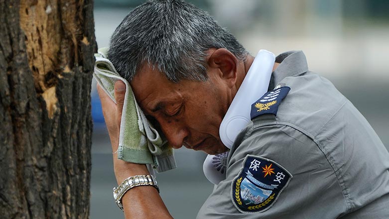 A security guard wearing an electric fan on his neck wipes his sweat on a hot day in Beijing, July 3, 2023. (Photo: AP/Andy Wong, File)
