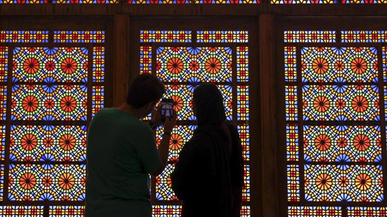 A man and a woman stand in front a stained glass window at Dowlat Abad Garden in Iran's central city of Yazd, July 3, 2023. (Photo: Atta Kenare/AFP)
