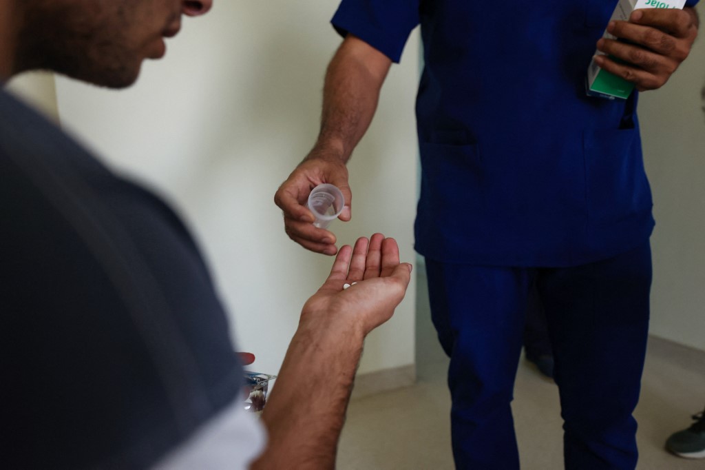 A patient receives his doze of medication from a health worker at the Al-Canal Center for Social Rehabilitation in Baghdad, July 11, 2023. (Photo: Ahmad Al-Rubaye/AFP)