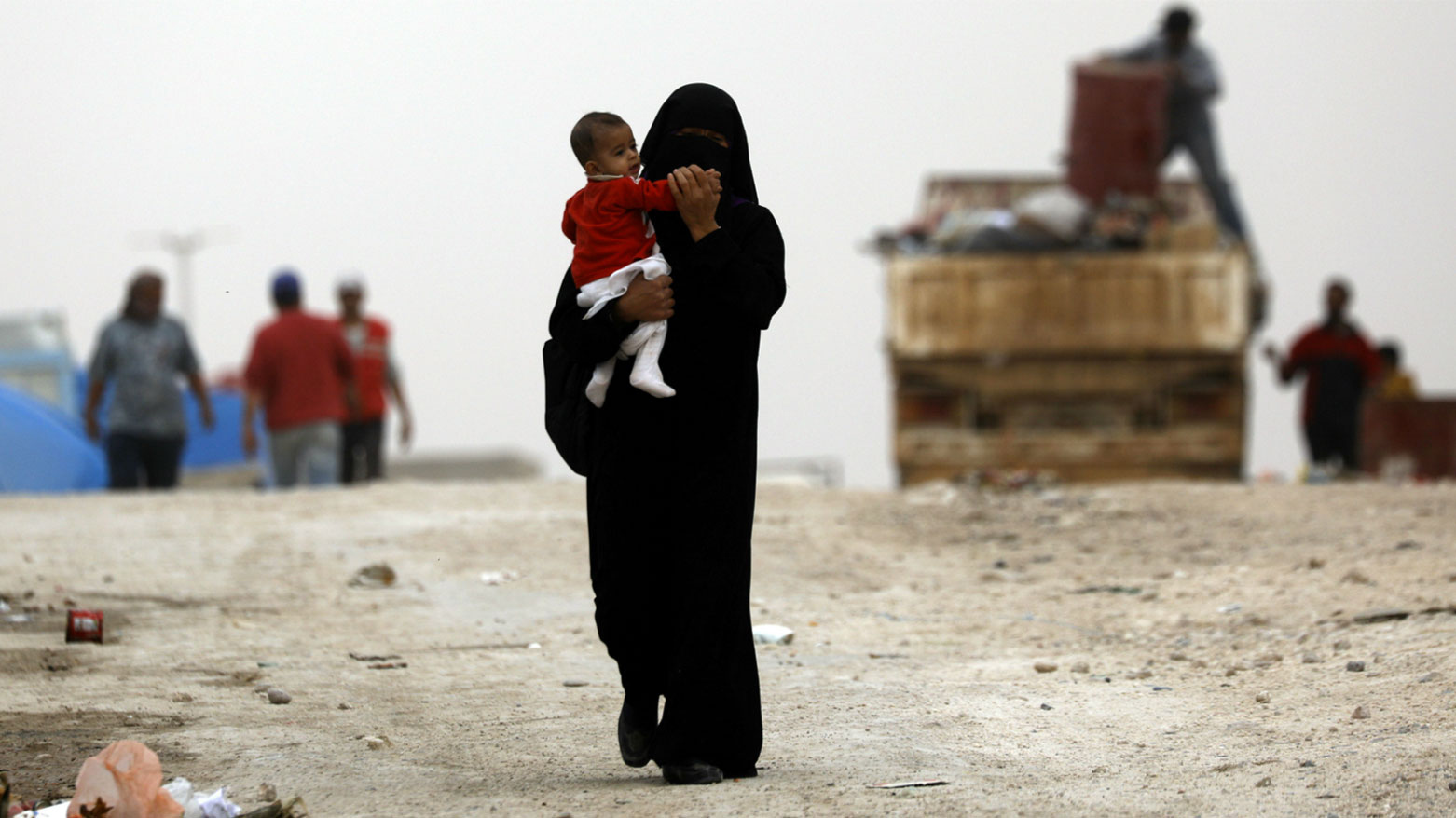 إحدى زوجات مسلحي داعش تحمل طفلاً في إحدى مخيمات شمال شرقي سوريا (فرانس برس)