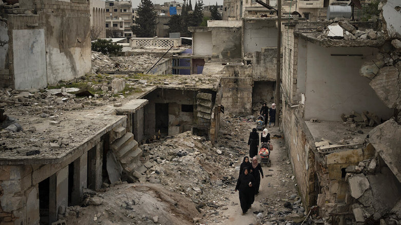 In this March 12, 2020 photo, women walk in a neighborhood heavily damaged by airstrikes in Idlib, Syria. (Photo: Felipe Dana/AP)