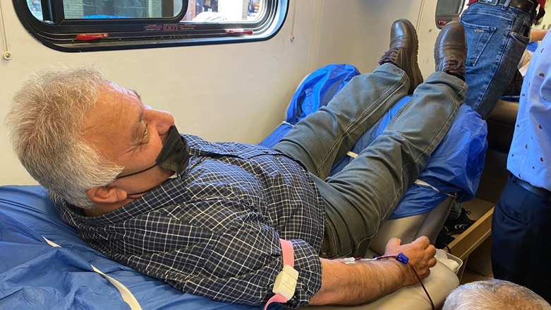 A blood donor lays back on a medical bed as blood is withdrawn as part of the Kurdistan Region's capital Erbil campaign marking World Blood Donor Day, June 14, 2021. (Photo: Renas Ali/Kurdistan 24)