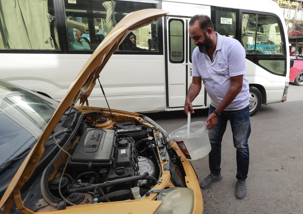 Osama Mohammed, an Iraqi taxi driver, adds water in the radiator of his vehicle, in the capital Baghdad, May 31, 2022. (Photo: Ahmad Al-Rubaye/AFP)