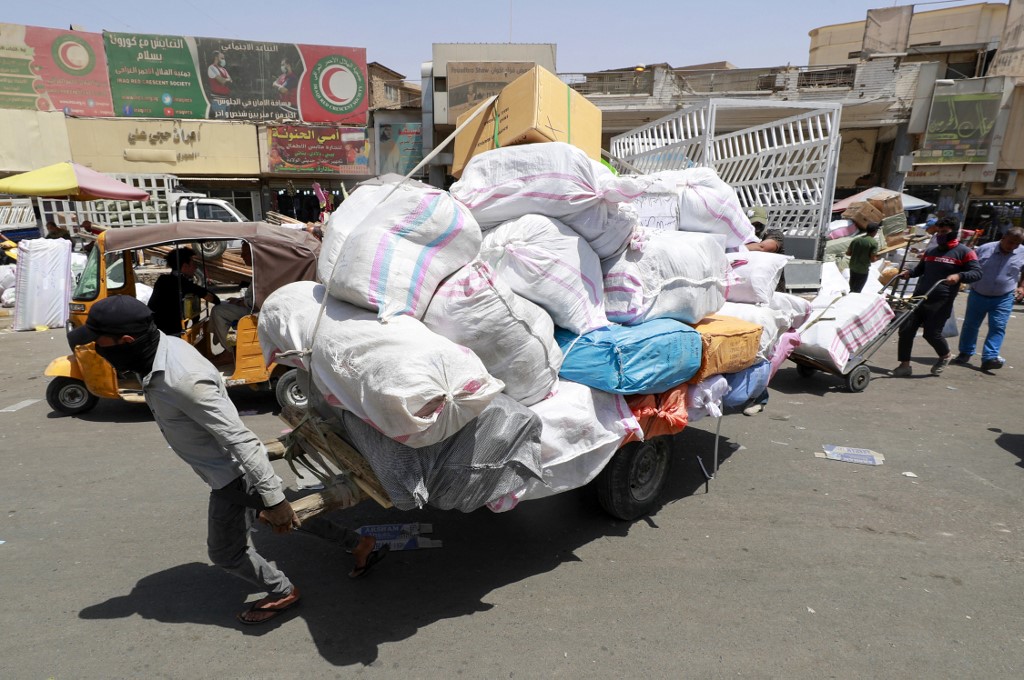 An Iraqi porter transports an order in the capital Baghdad, June 11, 2022. (Photo: Ahmad Al-Rubaye/AFP)