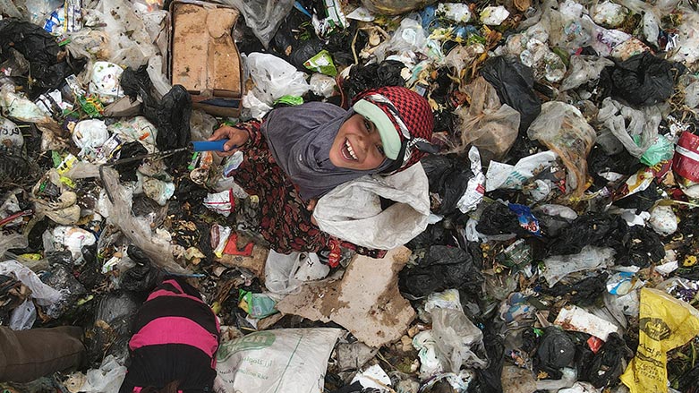 A child smiles as she sifts through the rubbish with a scythe, looking for plastic items to sell for recycling, at a dump site near the village of Hazreh in Syria's northwestern Idlib province. (Aaref Watad/ AFP)