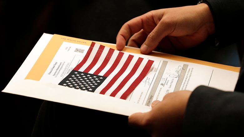 Abdullah Omar, from Iraq, holds his information packet and an American flag during a naturalization ceremony on Jan. 17, 2020, in Cleveland. (Photo: Tony Dejak/ AP)