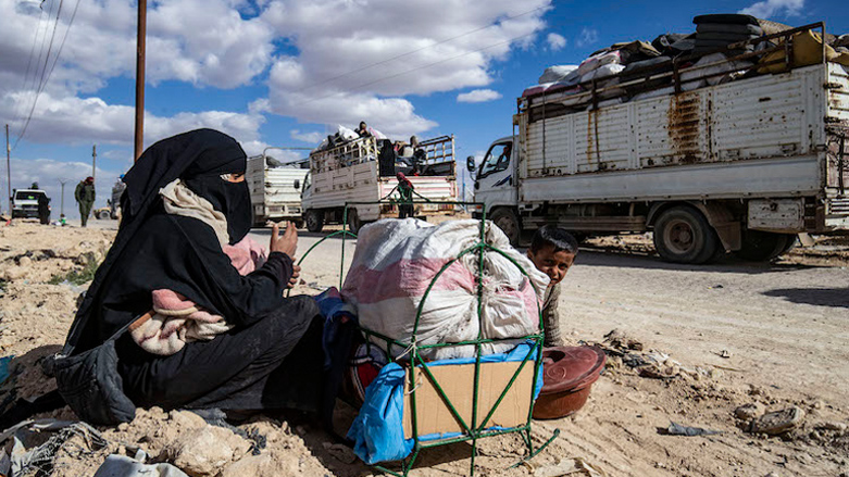 A Syrian woman and child sit by their belongings awaiting departure from the Kurdish-run al-Hol camp on March 18, 2021. (Photo: Delil Souleiman/AFP)