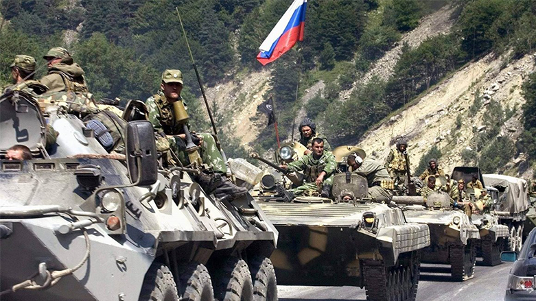 جنود يستقلّون مدرعات ترفع العلم الروسي