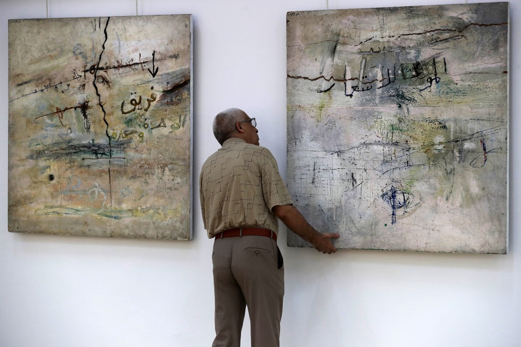 A man adjusting a painting by Iraqi artist Shakir Hassan al-Saïd, entitled 