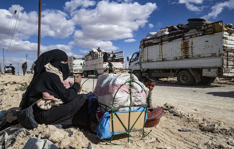A Syrian woman and child sit by their belongings awaiting departure, as another group of Syrian families is released from the Kurdish-run al-Hol camp on March 18, 2021. (Photo: Delil SOULEIMAN / AFP)