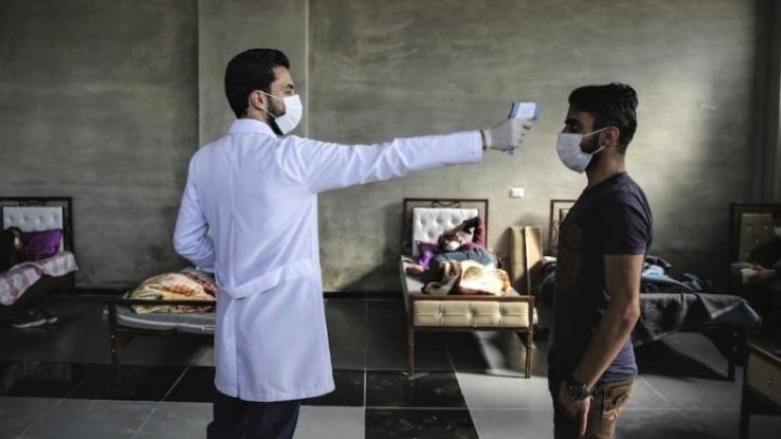 A health  are worker checks the temperature of a man inside a health isolation center on the Syrian-Turkish border. (Photo: AP/Anas Alkharboutli)