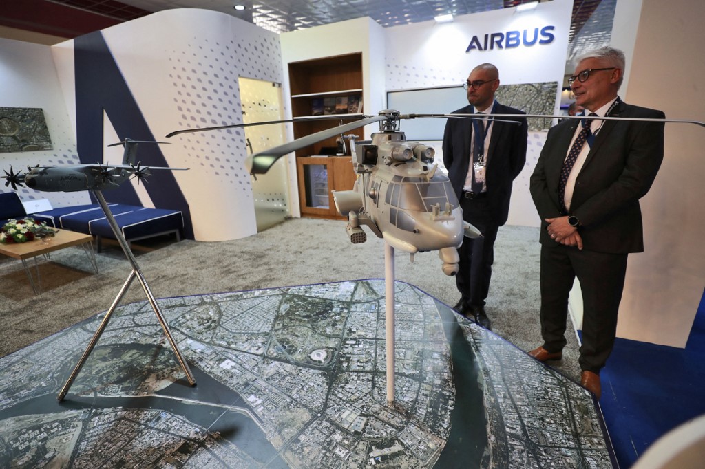 Representatives from French arms and military manufacturers stand near models of weapons at their stand during the 10th edition of the Baghdad security, defence and military industry fair March 2, 2022. (Photo: Ahmad al-Rubaye/AFP)