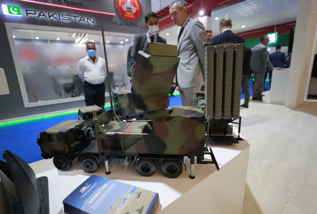 Representatives from French arms and military manufacturers stand near models of weapons at their stand during the 10th edition of the Baghdad security, defence and military industry fair on March 2, 2022. (Photo: Ahmad al-Rubaye/AFP)