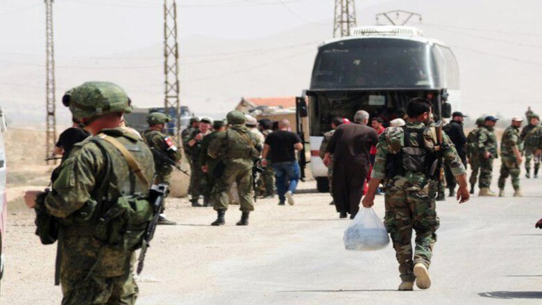 Russian soldiers and Syrian government forces gathering next to a bus during the evacuation of rebel fighters and their families from the town of Dumayr, Syria, April 19, 2018. (Photo: SANA via AP)