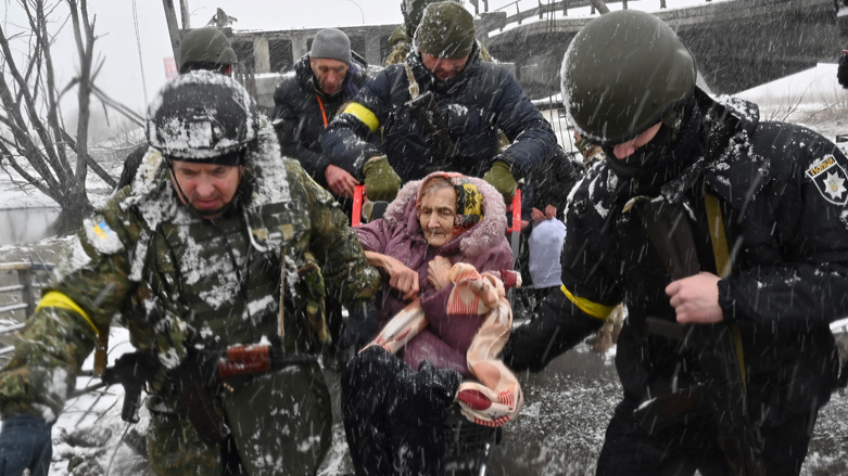 Ukrainian soldiers help an elderly woman to cross a destroyed bridge as she evacuates the city of Irpin, northwest of Kyiv, March 8, 2022. (Photo: Sergei Supinsky/AFP)