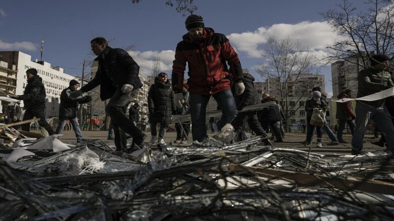 People clear debris outside a medical center damaged after parts of a Russian missile, shot down by Ukrainian air defense, landed on a nearby apartment block, Kyiv, Ukraine, Mar. 17, 2022. (Photo: Vadim Ghirda/AP)